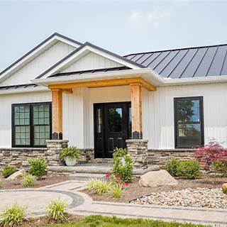 Exterior of home with black-framed ProVia windows contrasted against white siding and stone accents.
